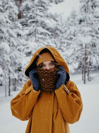 Portrait of woman in warm clothing standing against trees during winter