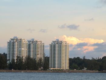 Buildings by lake against sky in city