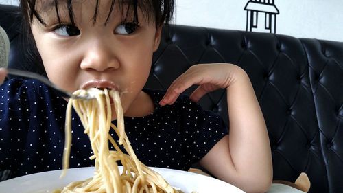 Cute girl eating noodles at home