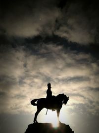 Low angle view of silhouette statue against sky