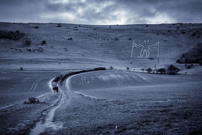 Road on snow covered land against sky