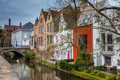 Arch bridge over river amidst buildings against sky