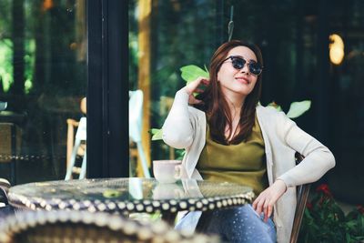 Portrait of young woman wearing sunglasses while sitting at home