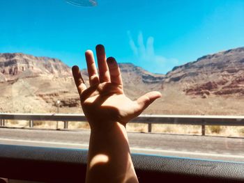 Midsection of person hand against sky seen through car window