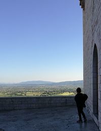 Full length of man standing on mountain against clear sky