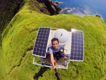 High angle view portrait of man standing amidst solar panels on light house