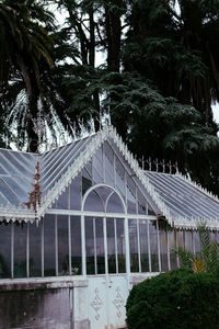 Built structure by trees and plants against sky