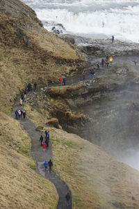 High angle view of people standing on footpath by mountain at gullfoss waterfall