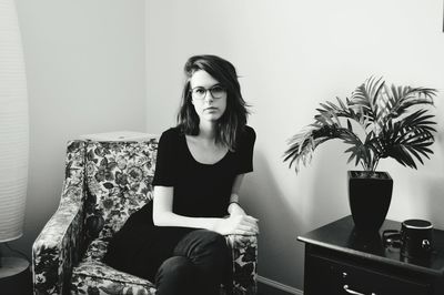 Portrait of young woman sitting on sofa at home