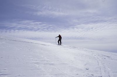 Full length of man walking on snowcapped landscape against sky during winter