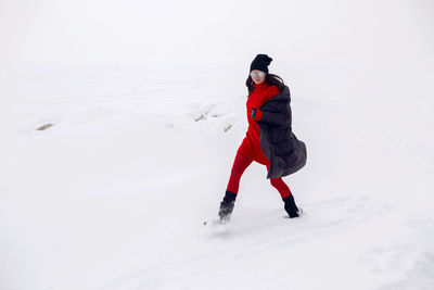 Girl running in a snowy field in a jacket and sunglasses