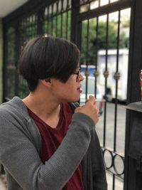 Man smoking while standing by gate