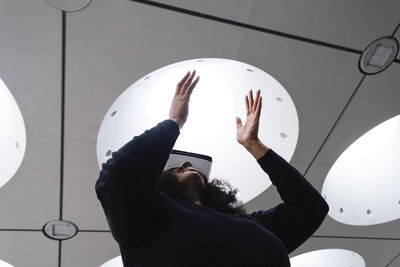 Woman wearing virtual reality simulator under illuminated ceiling