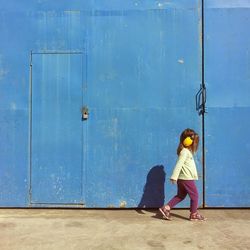 Woman standing against blue door