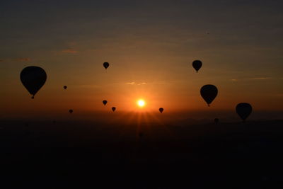 Hot air balloons flying against sky during sunset