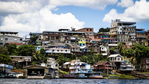 Buildings by river against sky