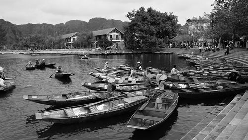 Boats moored in lake by buildings against sky