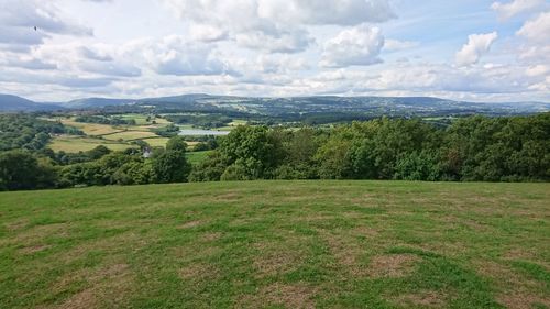 Scenic view of grassy field against cloudy sky