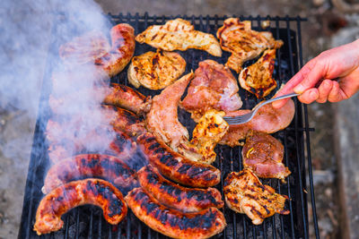 Cropped hand of person preparing food on barbecue grill