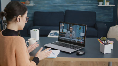 Young woman talking on video call through laptop at home