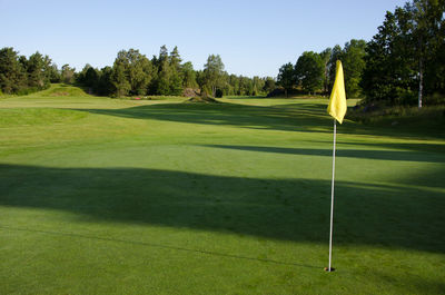 Yellow flag in hole on golf course against sky