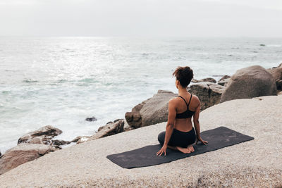 Side view of woman sitting at beach