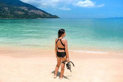 Rear view of woman on beach against sky