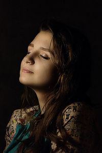 Young woman with eyes closed against black background