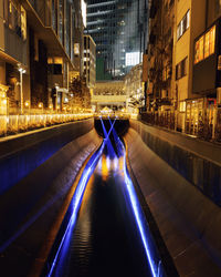 Light trails on street amidst buildings in city at night