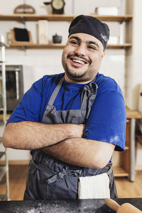 Smiling man with arms crossed standing in kitchen