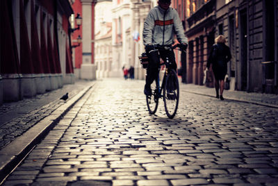 Man riding bicycle on street amidst buildings