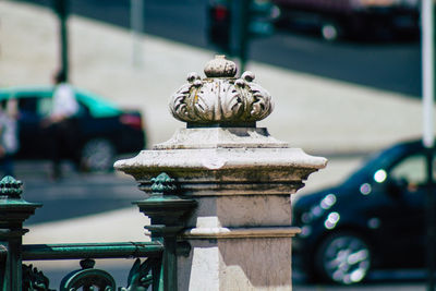 Close-up of old statue against railing in city