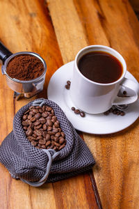 High angle view of coffee beans on table with a cup of coffee