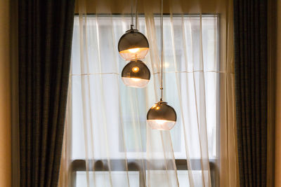 Low angle view of illuminated light bulb hanging from ceiling