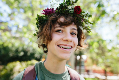 Smiling teen with braces wears a flower crown outside