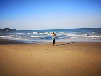 Rear view of man carrying daughter on shore at beach