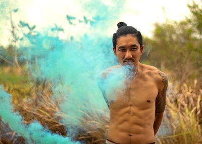 Shirtless man with distress flare standing in forest