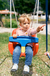 Boy playing on swing at playground