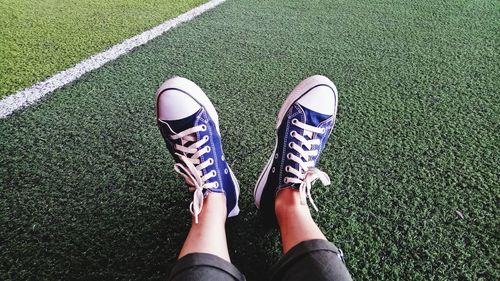 Low section of woman wearing shoes on field