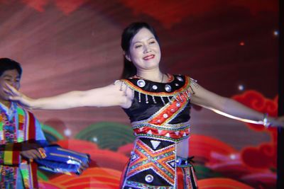 Smiling woman in traditional clothing dancing on stage