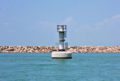 Lighthouse by sea against clear sky