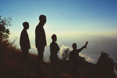 Silhouette people standing against sky during sunset