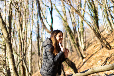 Full length of smiling woman standing by tree