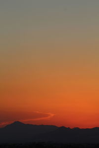 Scenic view of silhouette mountains against orange sky