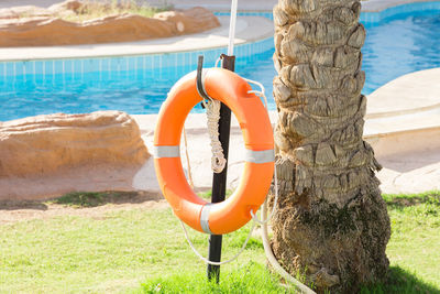 Orange emergency lifebuoy hanging on fence near pool on vacation at the hotel