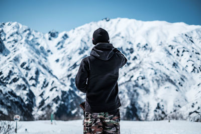 Rear view of man standing on snow covered mountain