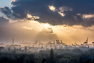 Industry against sky during sunset