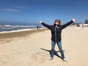 Smiling woman with arms outstretched standing on beach