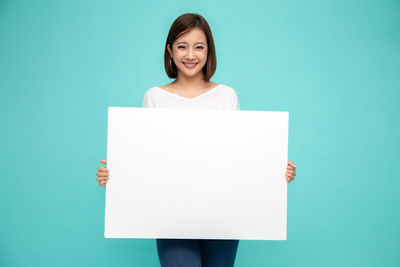 Portrait of smiling woman standing against blue background