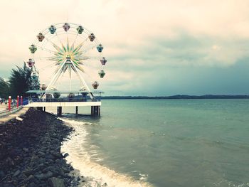 View of amusement park by sea against sky